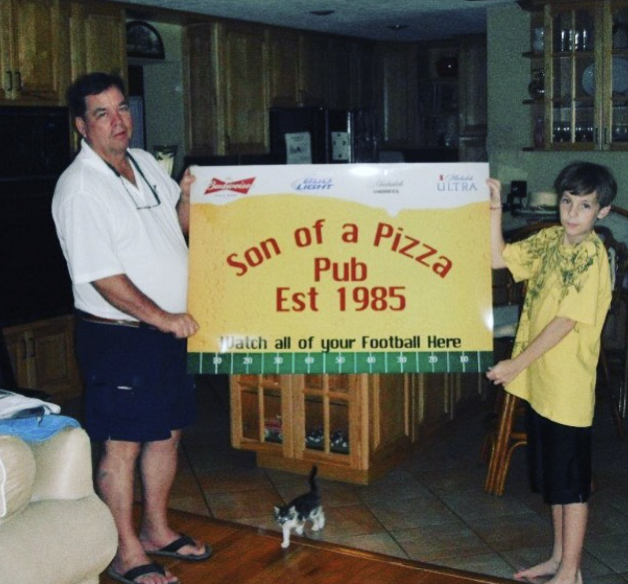 Mike Page and son holding the Son of a Pizza Pub banner